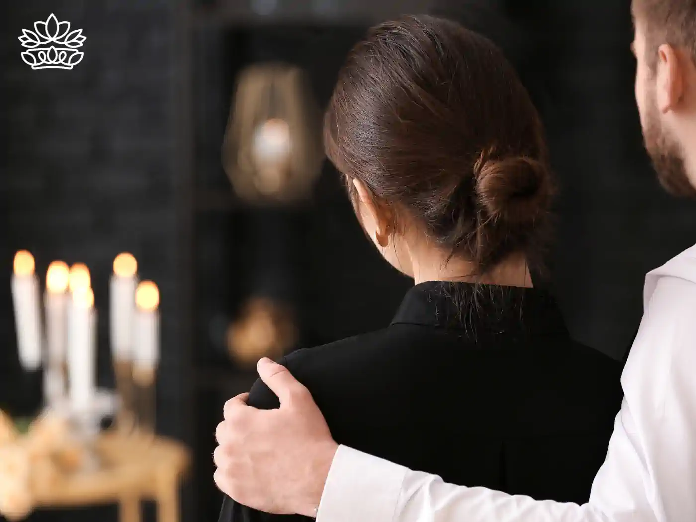 Couple embracing during a funeral with candles in the background. Fabulous Flowers and Gifts Funeral Collection.