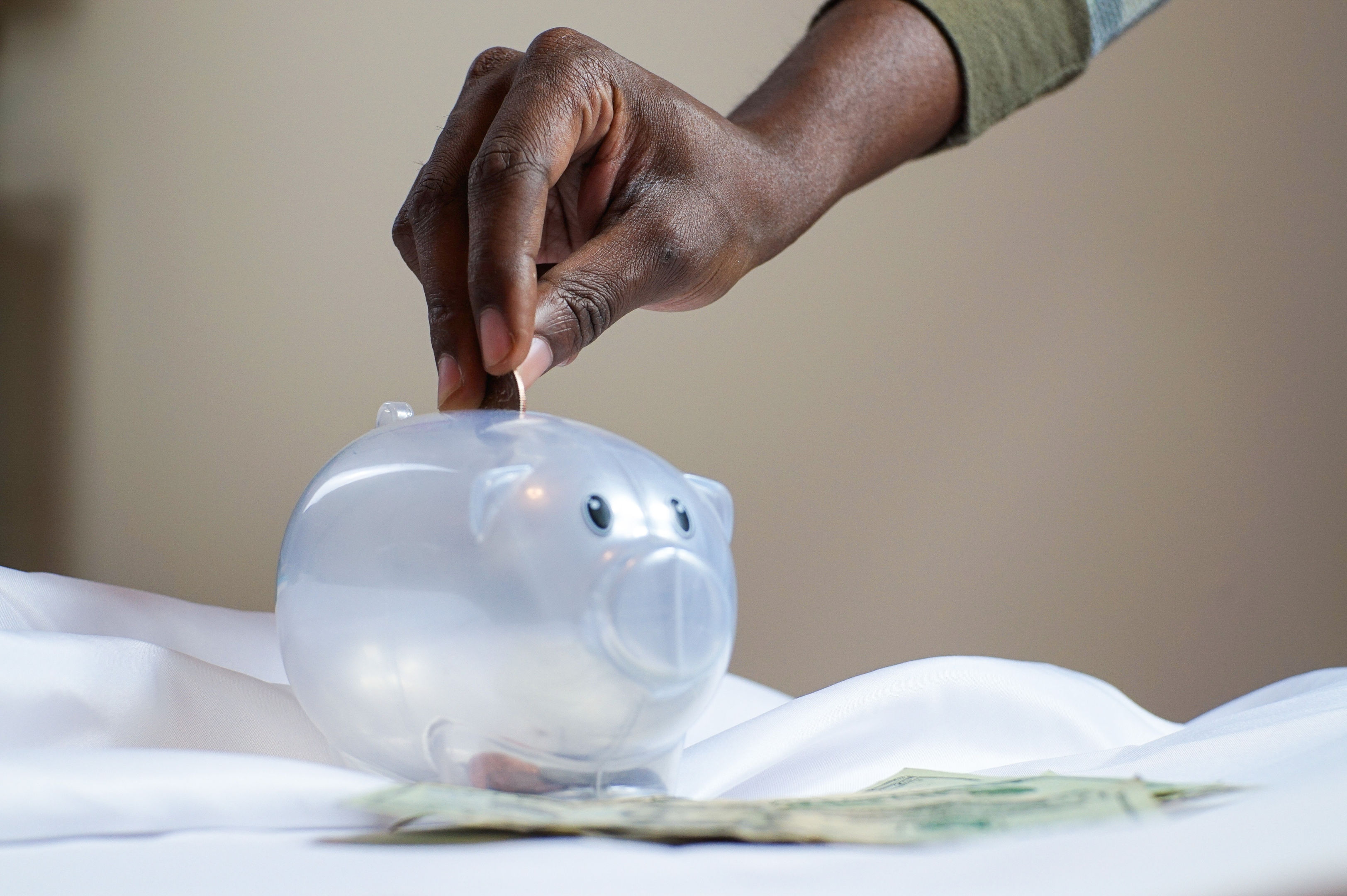 Start saving early - person putting a coin in a piggy bank