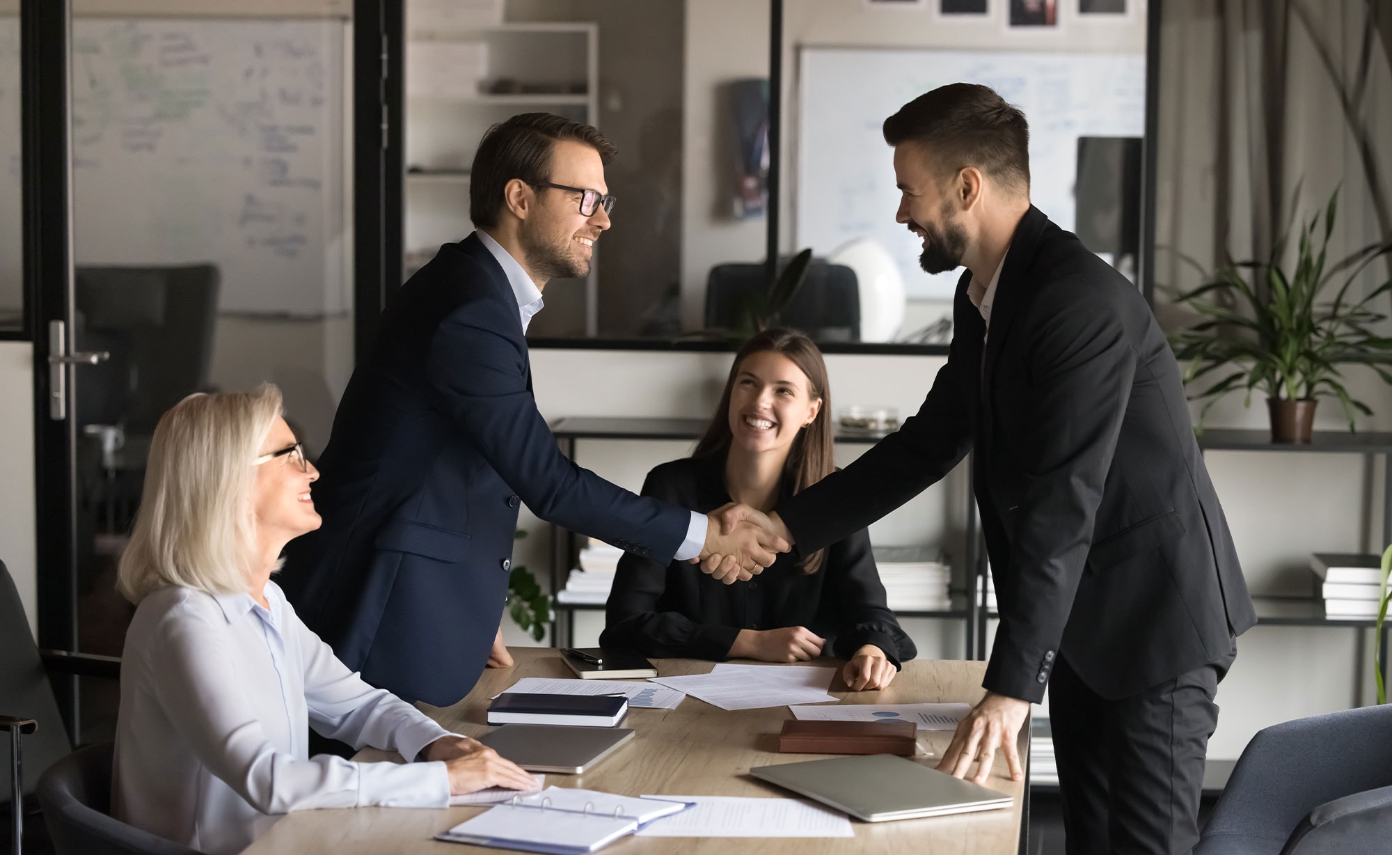 Team members shaking hands after a successful meeting, highlighting collaboration through insurance agency management systems.