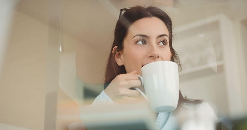 A woman drinking her morning coffee, she is calmly reflecting her day.