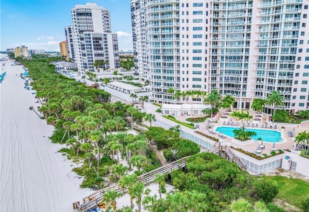 The image depicts an elegant gated community entrance featuring manicured landscaping and luxury signage, symbolizing the prestigious lifestyle of Pelican Bay Naples real estate. This inviting entrance showcases the refined luxury and modern sophistication that characterize the exclusive enclave.