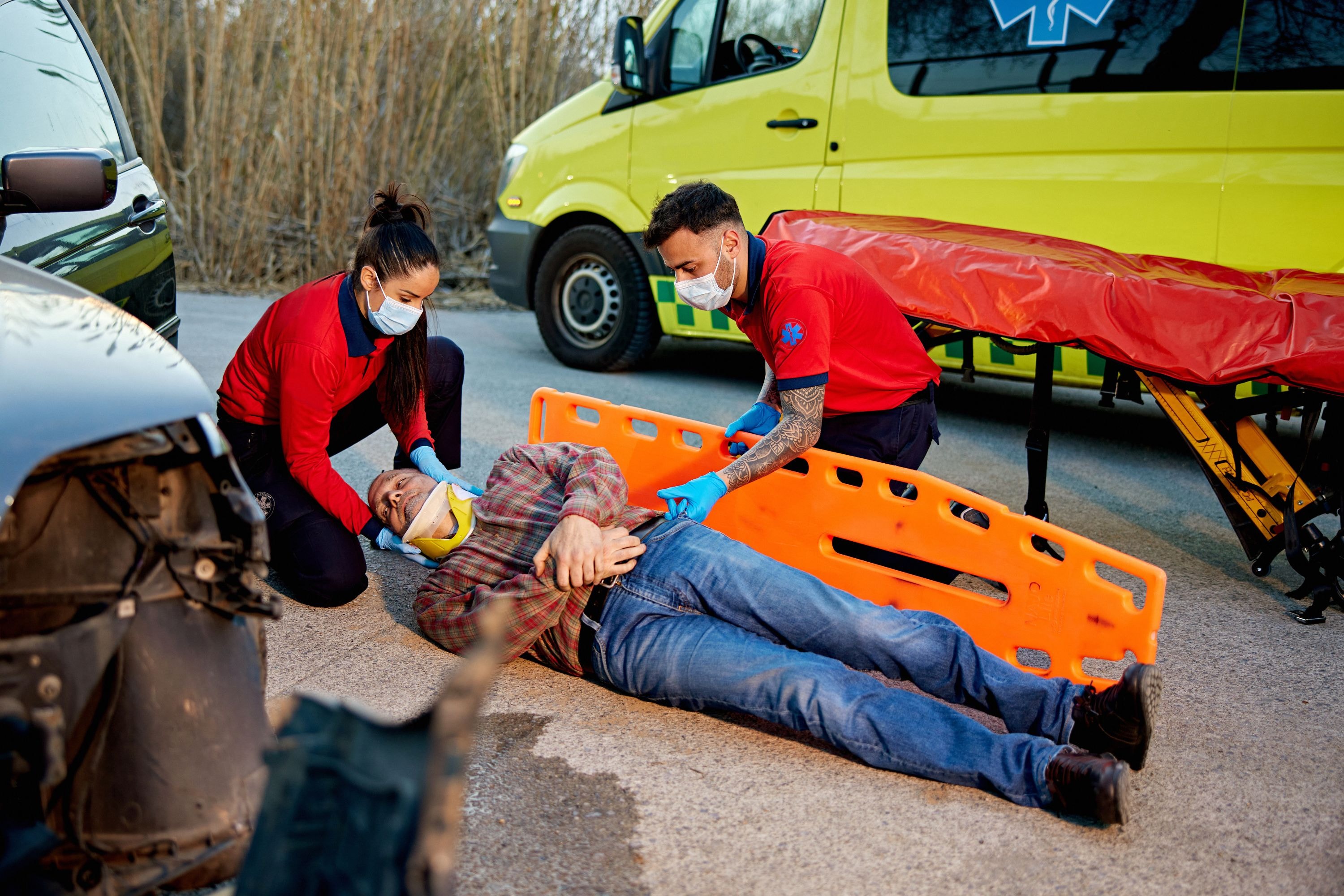 EMS team securing a trauma patient onto a spinal board during roadside rescue, highlighting the role of spinal boards in ensuring patient care, immobilization, and safety.