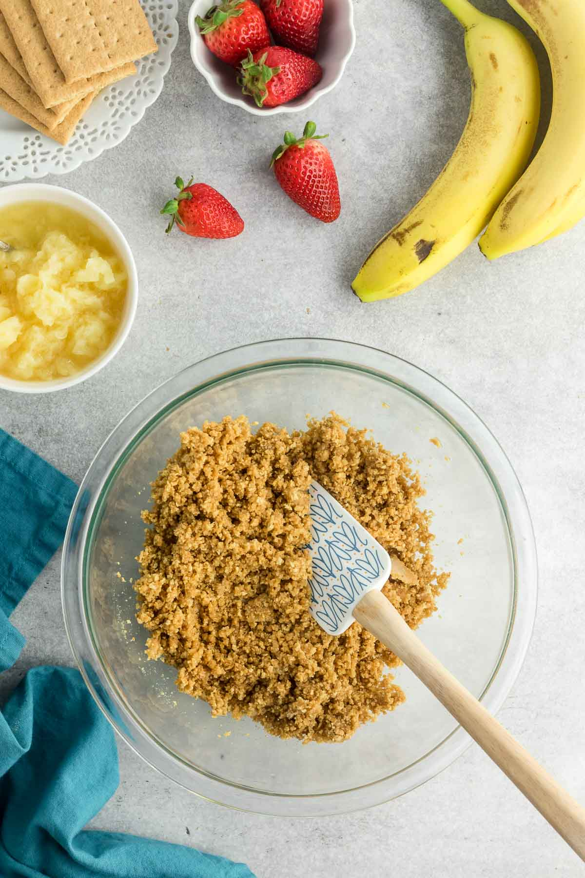 bowl of graham cracker crust mixture in bowl with spatula