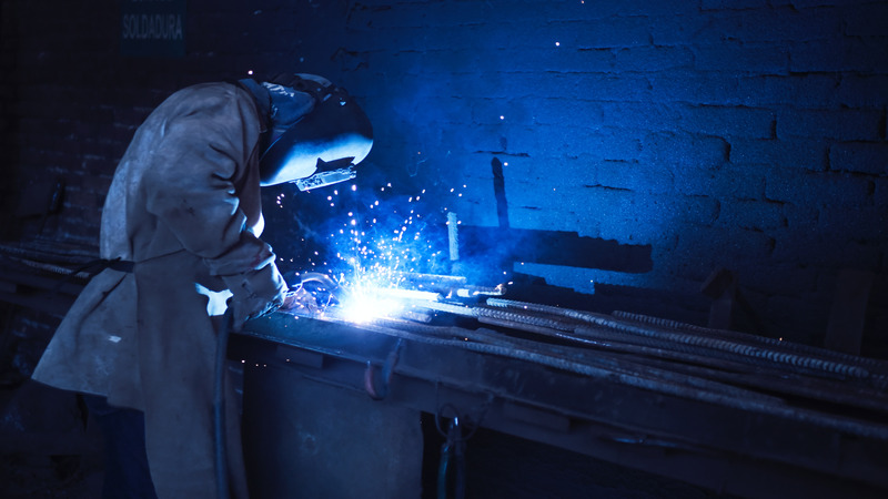 A welder working on metal rods by using backstep welding