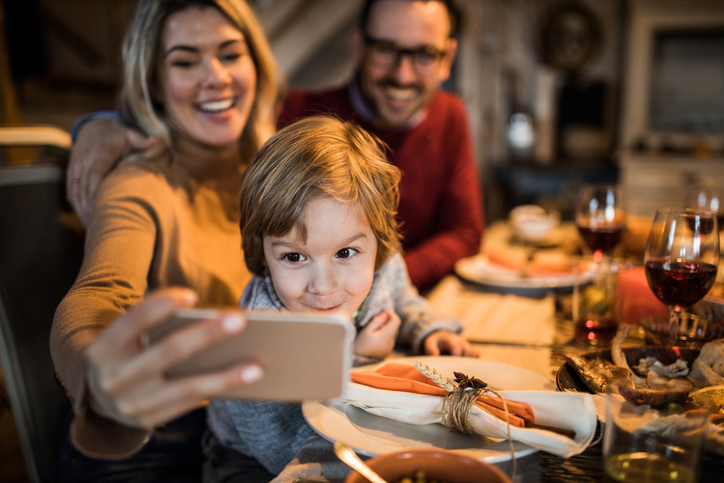 Family snapping a selfie at a holiday dinner table.