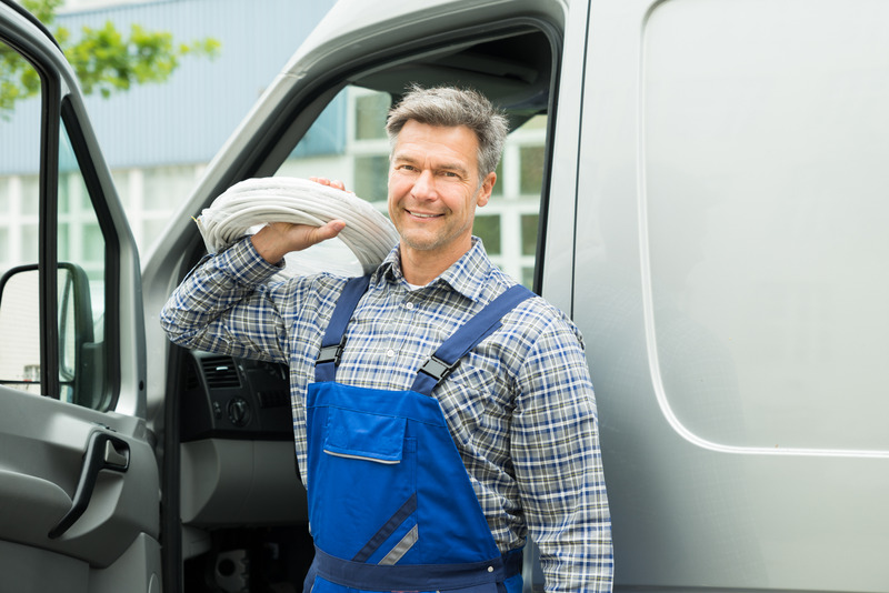 Lächelnder Handwerker neben Servicefahrzeug.