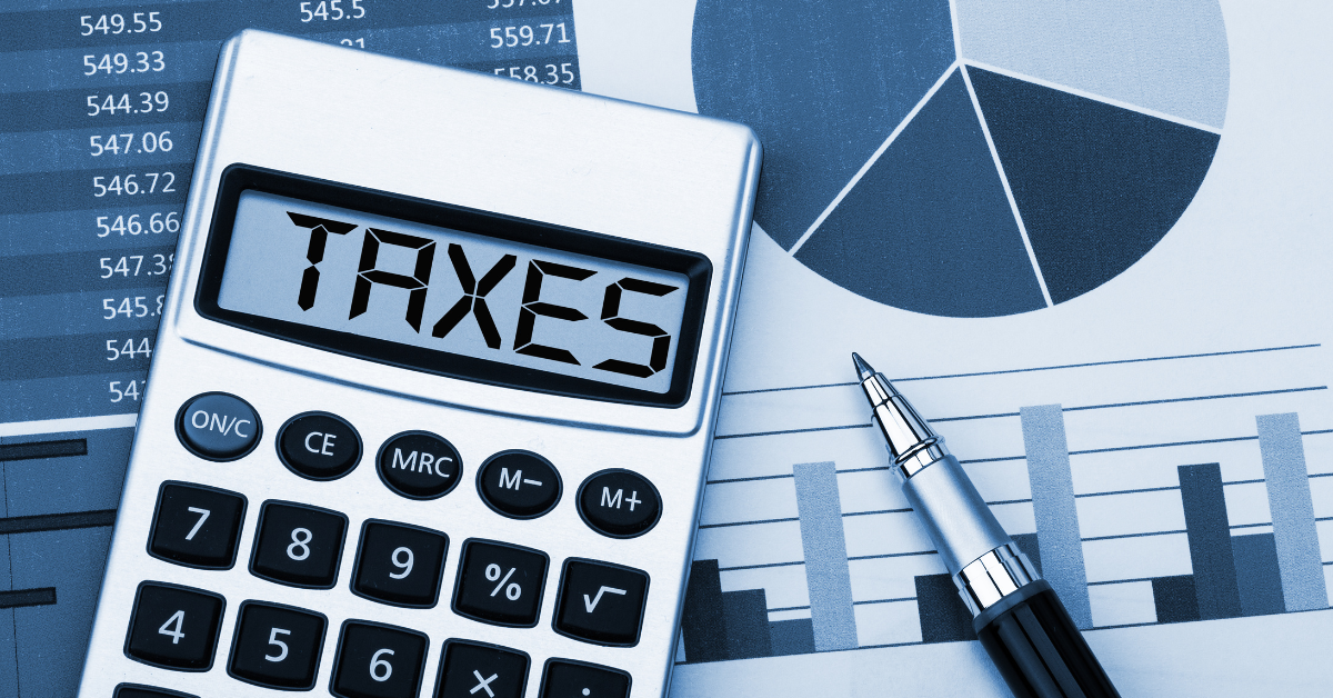 Calculator with the word “TAXES,” a pen, and charts with numbers, illustrating what is the difference between payroll tax and income tax.