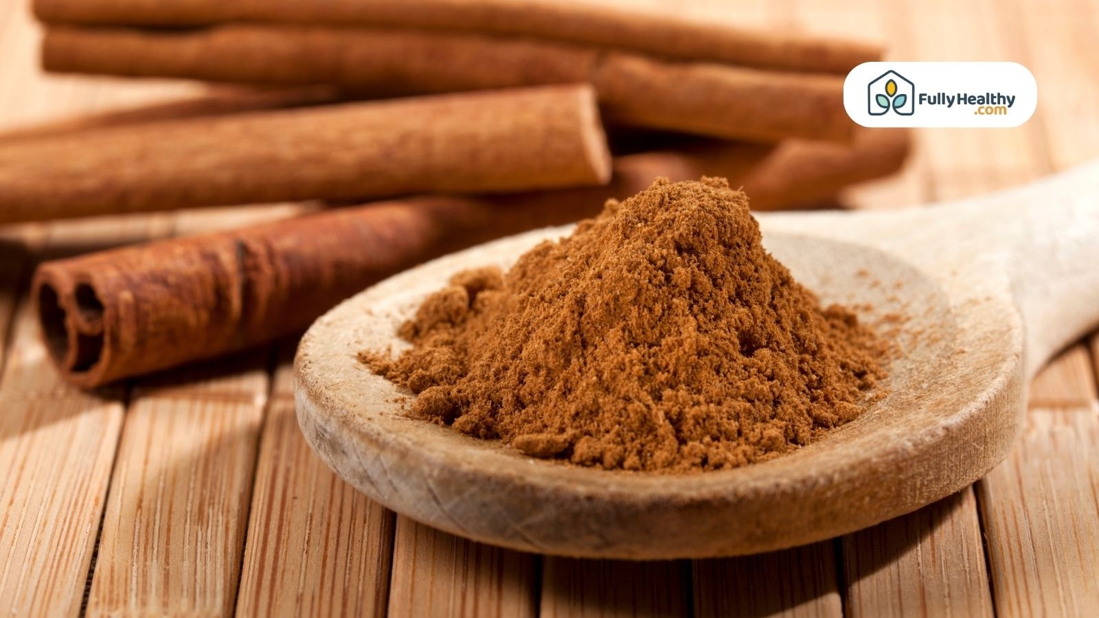 Ground cinnamon on wooden spoon with cinnamon sticks in background