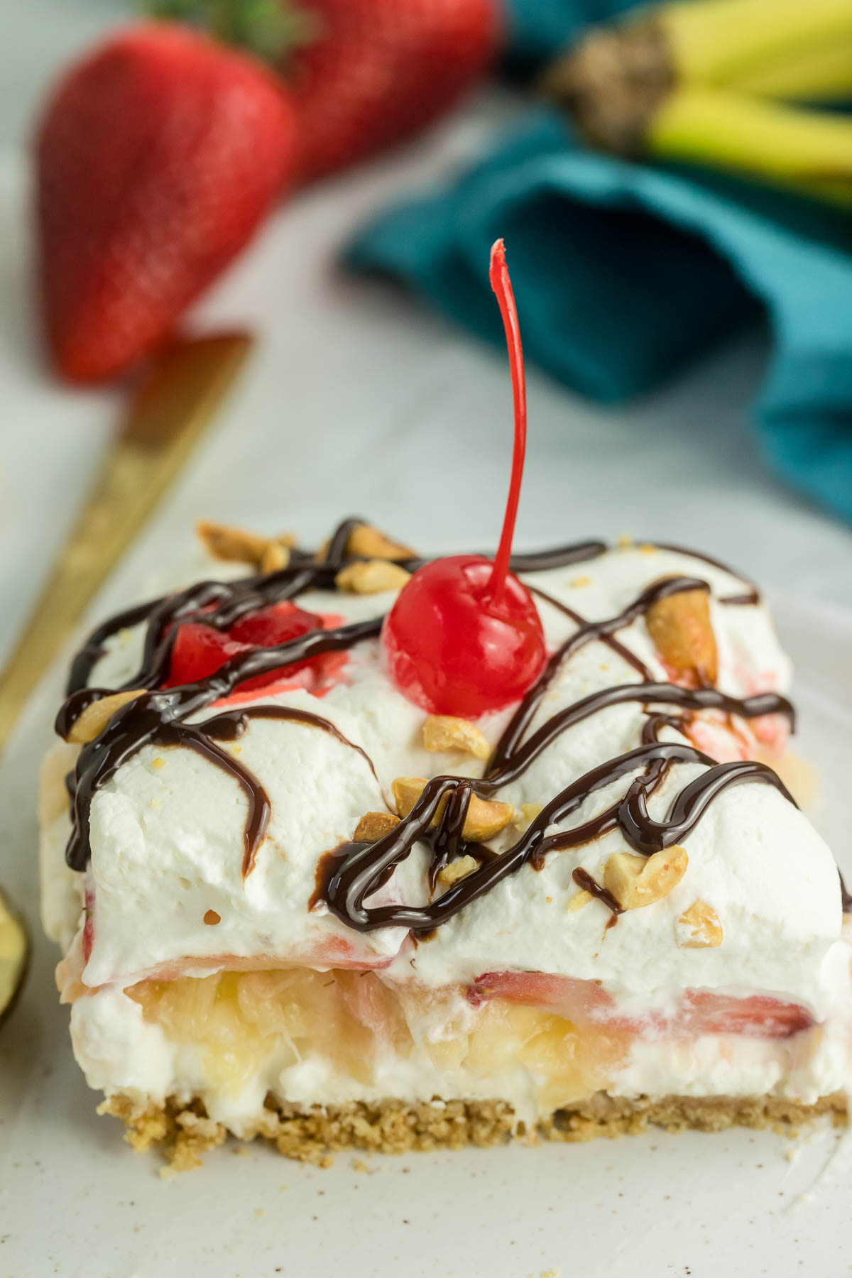 slice of banana split cake on a plate topped with cherry