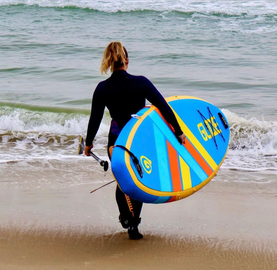 woman carrying a glide inflatable paddleboard