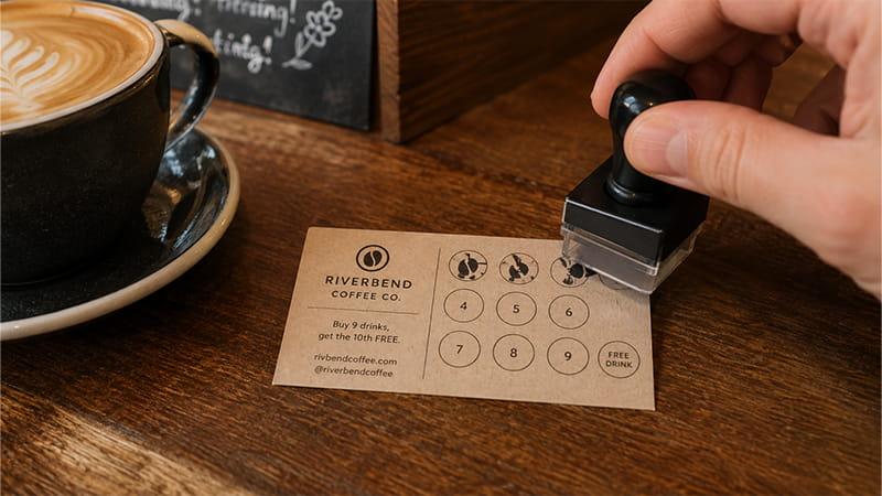 Coffee shop loyalty business card being stamped toward a free drink reward