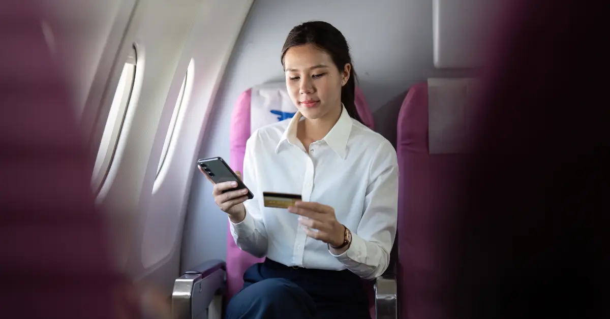 A woman holding a phone in one hand and a card in the other, illustrating OnlyFans payment methods.
