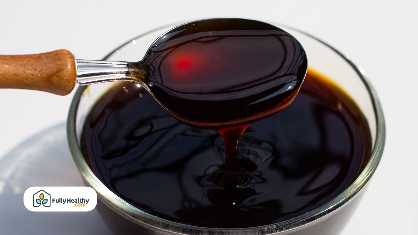 Spoon of thick oyster sauce over glass bowl