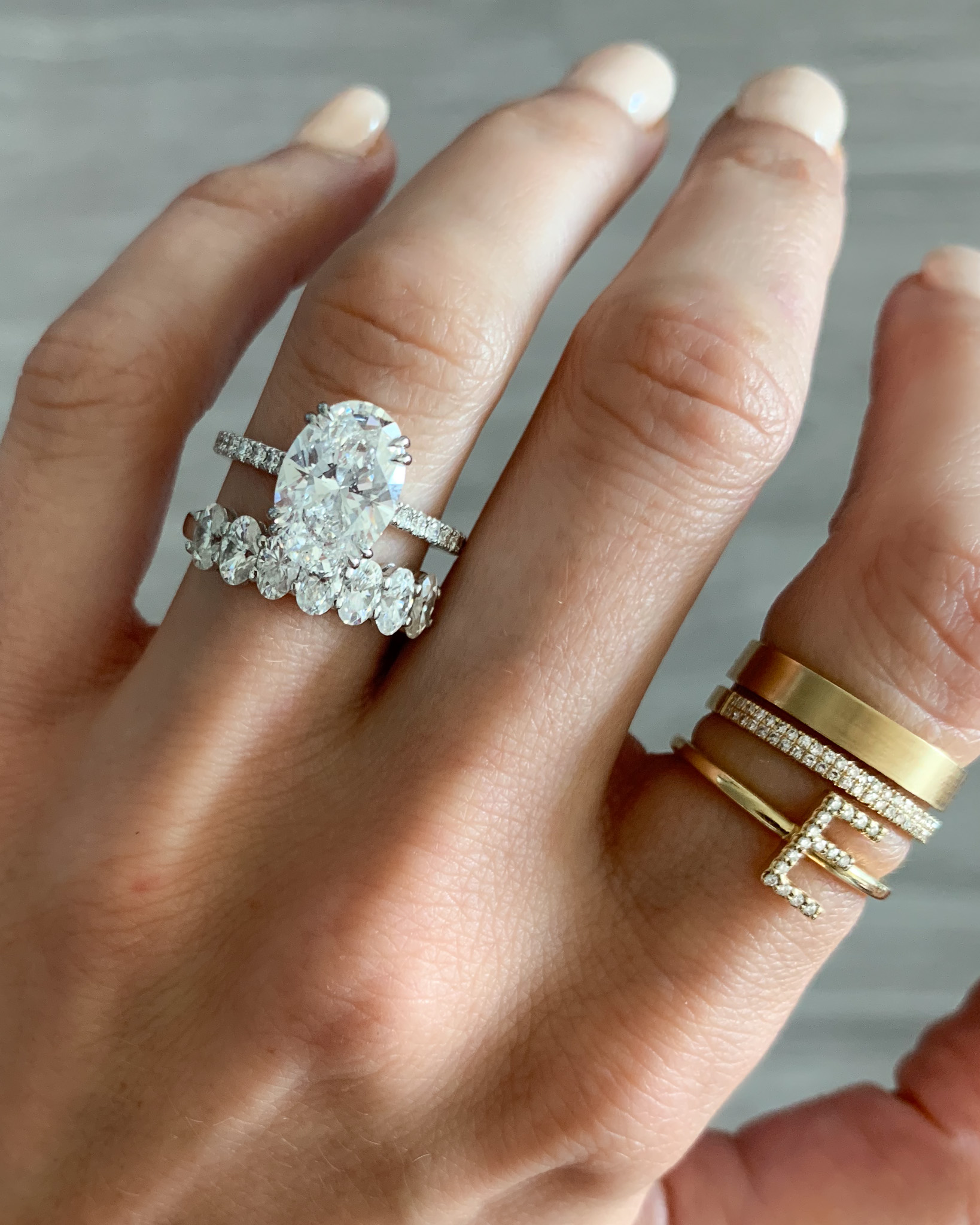 Un anillo de compromiso Pave con un diamante de talla ovalada y una alianza de diamantes ovalados.
