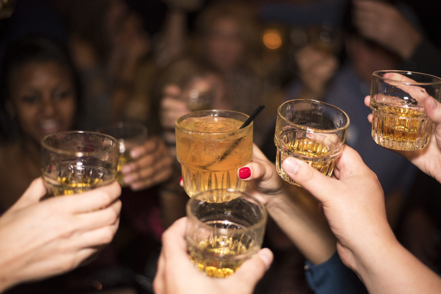 A group of people doing cheers with their drinks in a club.