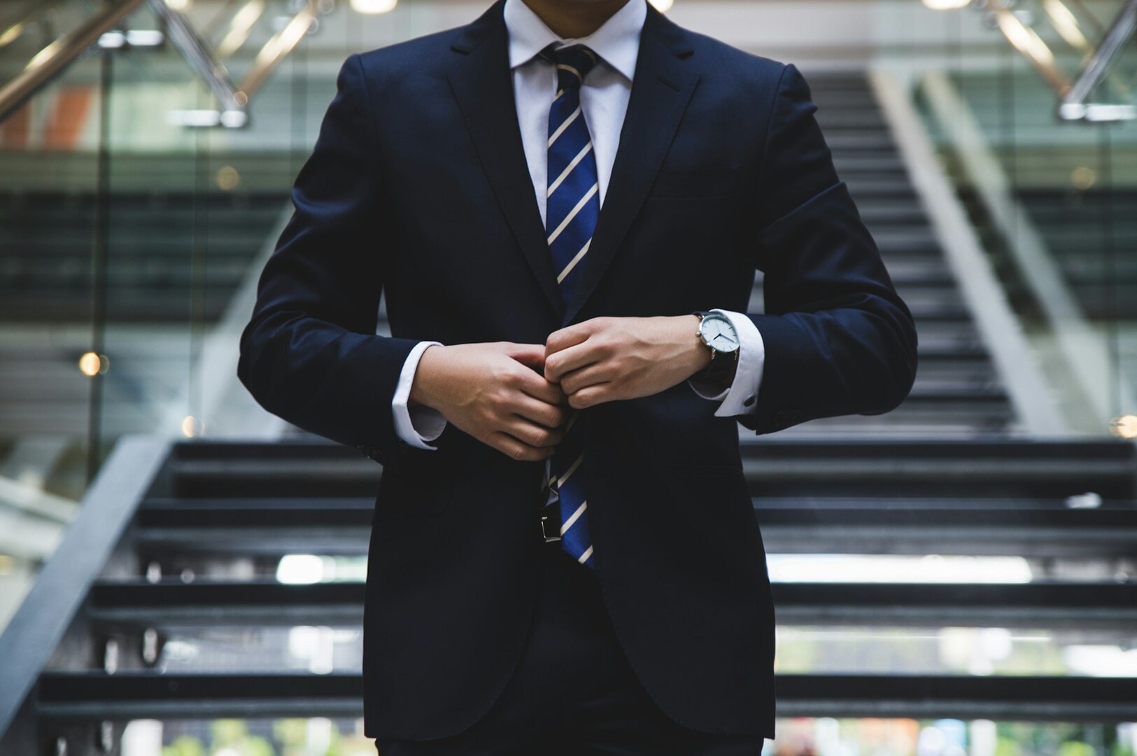 A well-dressed man in a suit and tie stands on stairs, representing the journey of career growth and success.