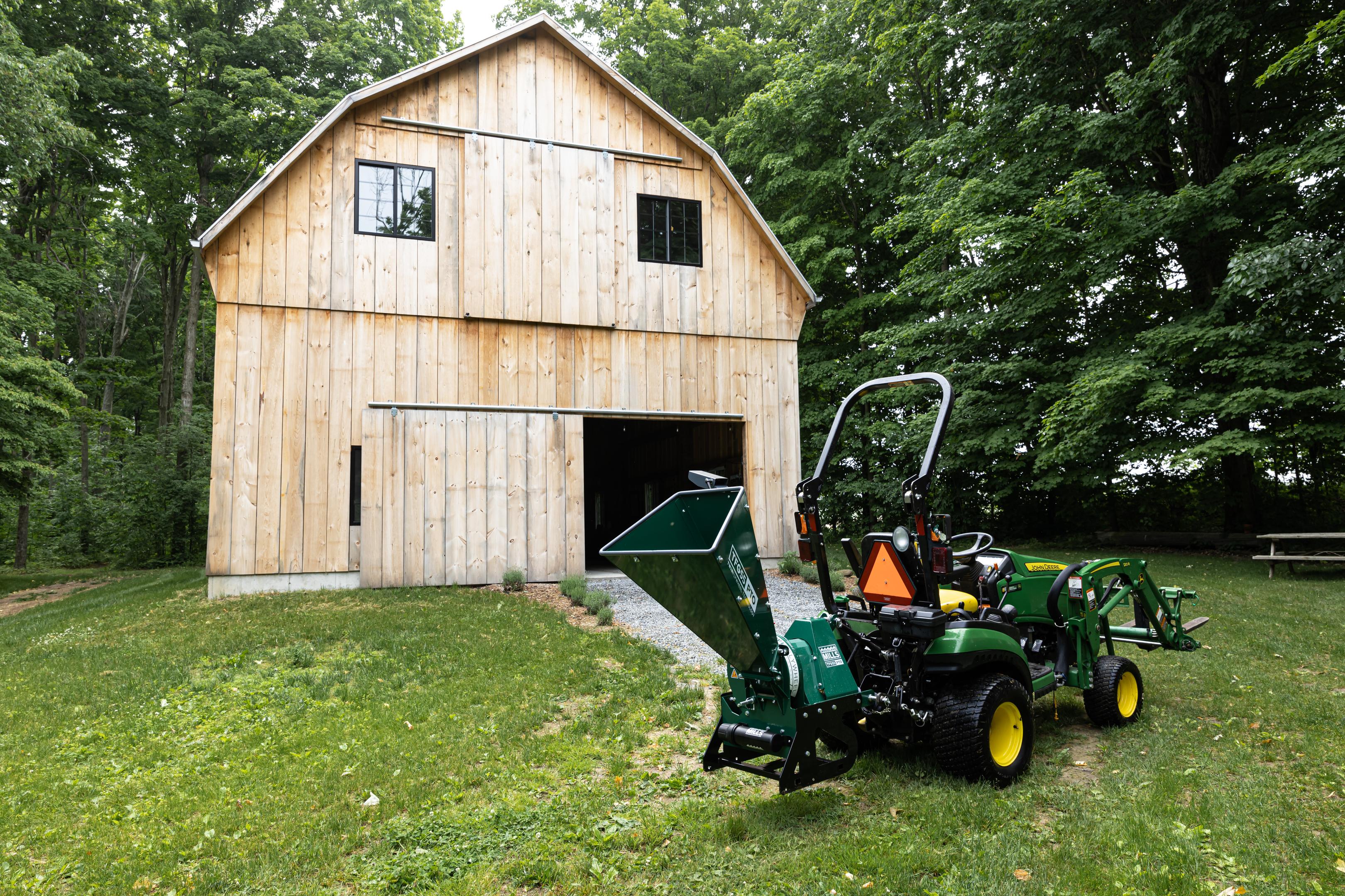 A barn with a Woodland Mills TFG55 GAS Wood Chipper in front of it.