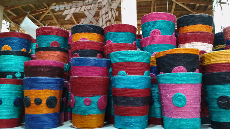 A large pile of colorful jute rugs in a warehouse