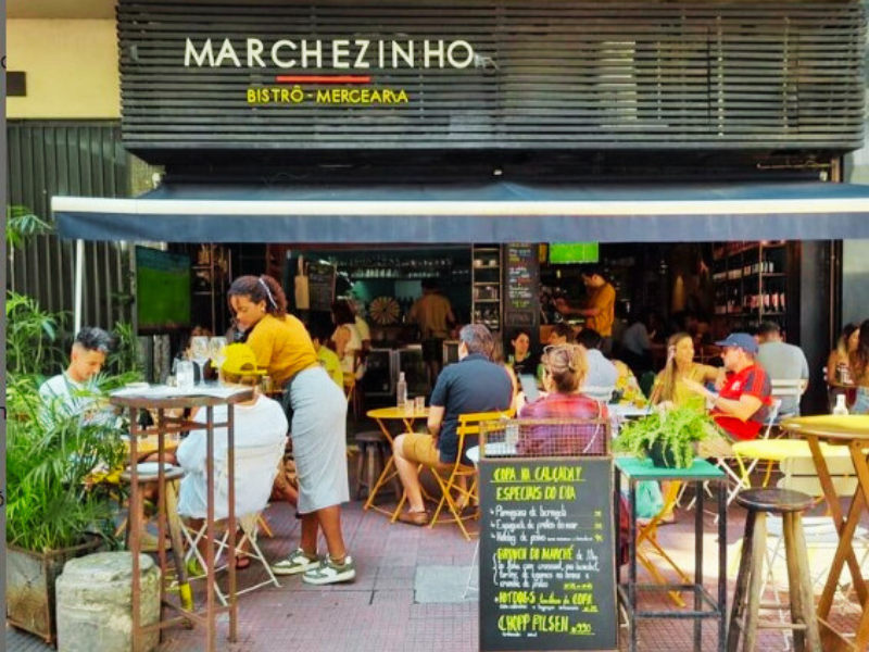 Fachada e clientes à mesa em frente ao Marchezinho Bistrô. Imagem: Reprodução Instagram. 