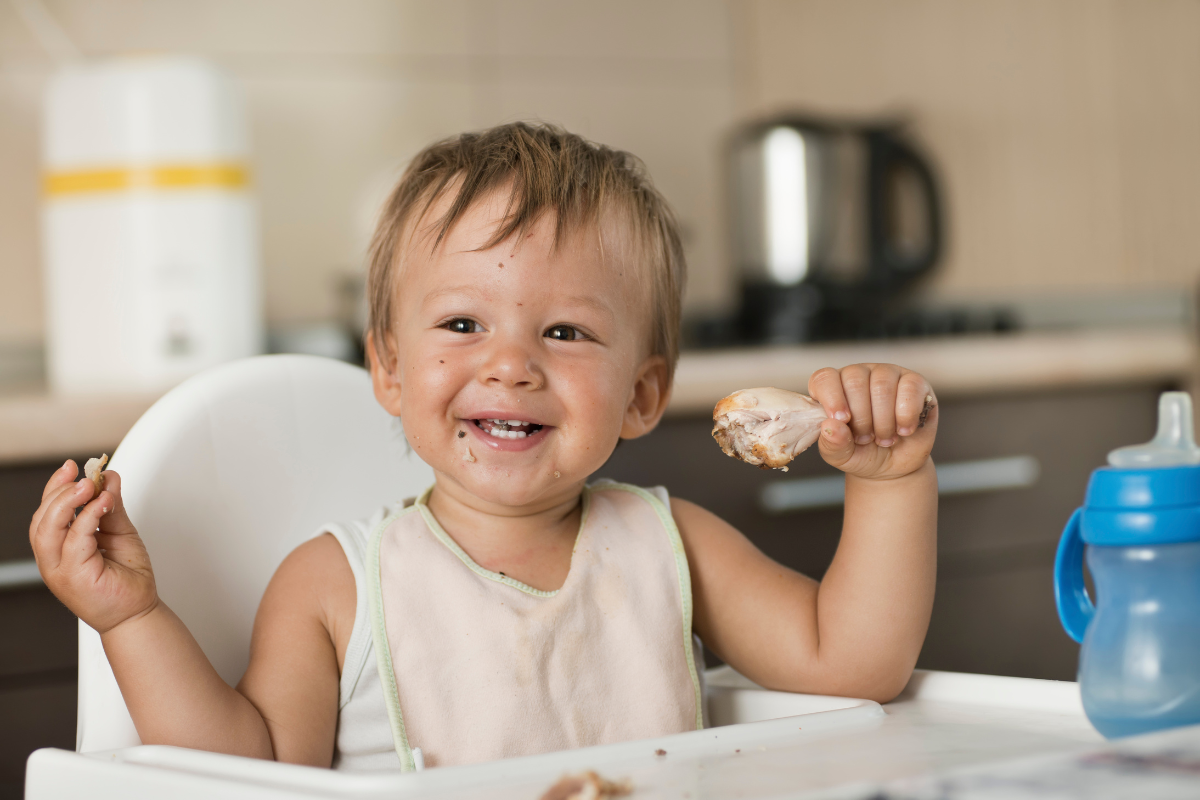 baby eating chicken wing off the bone
