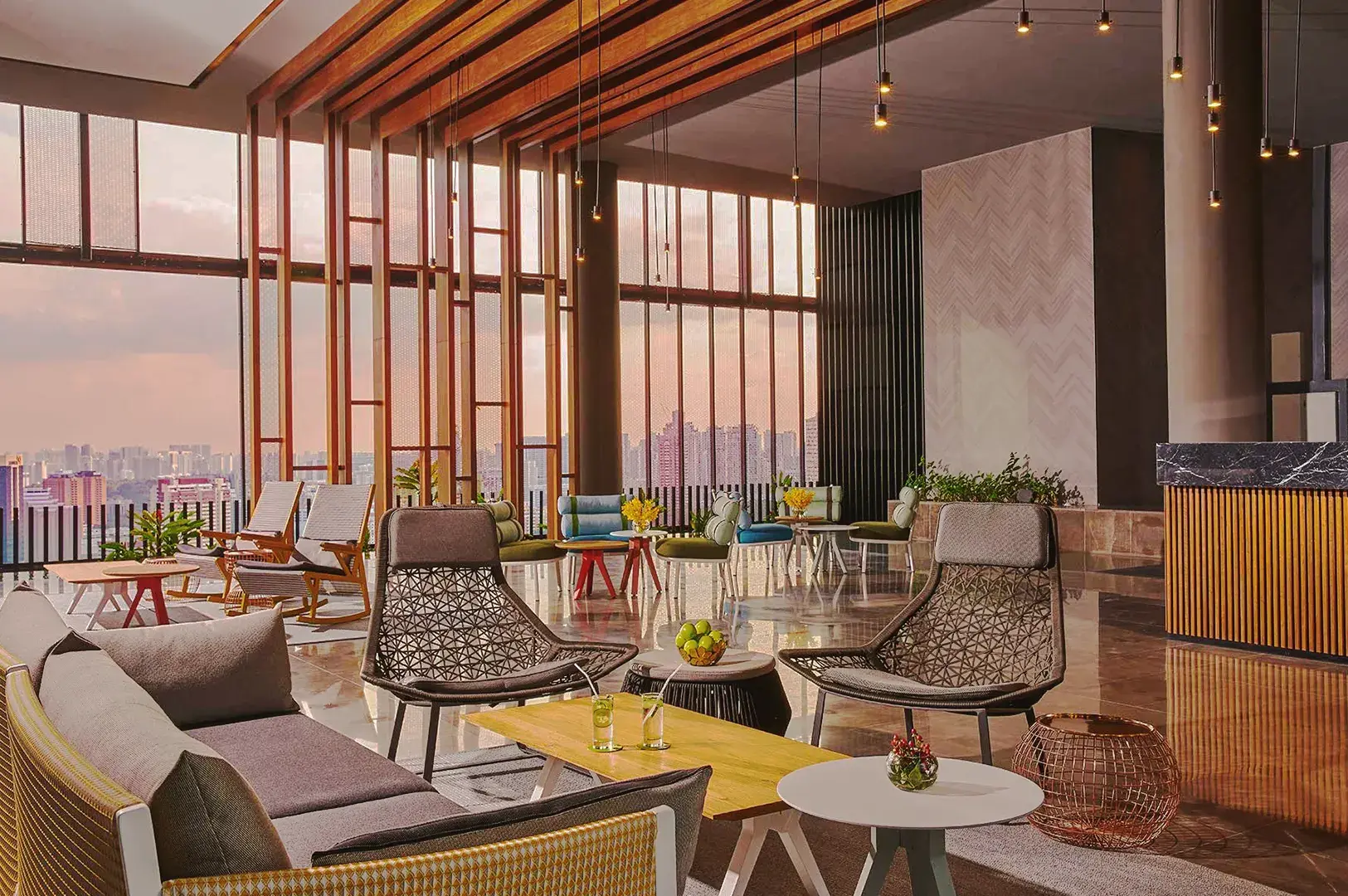 Stylish Oasia Hotel lounge in Singapore with sunset city view, modern furniture, and warm wooden accents.