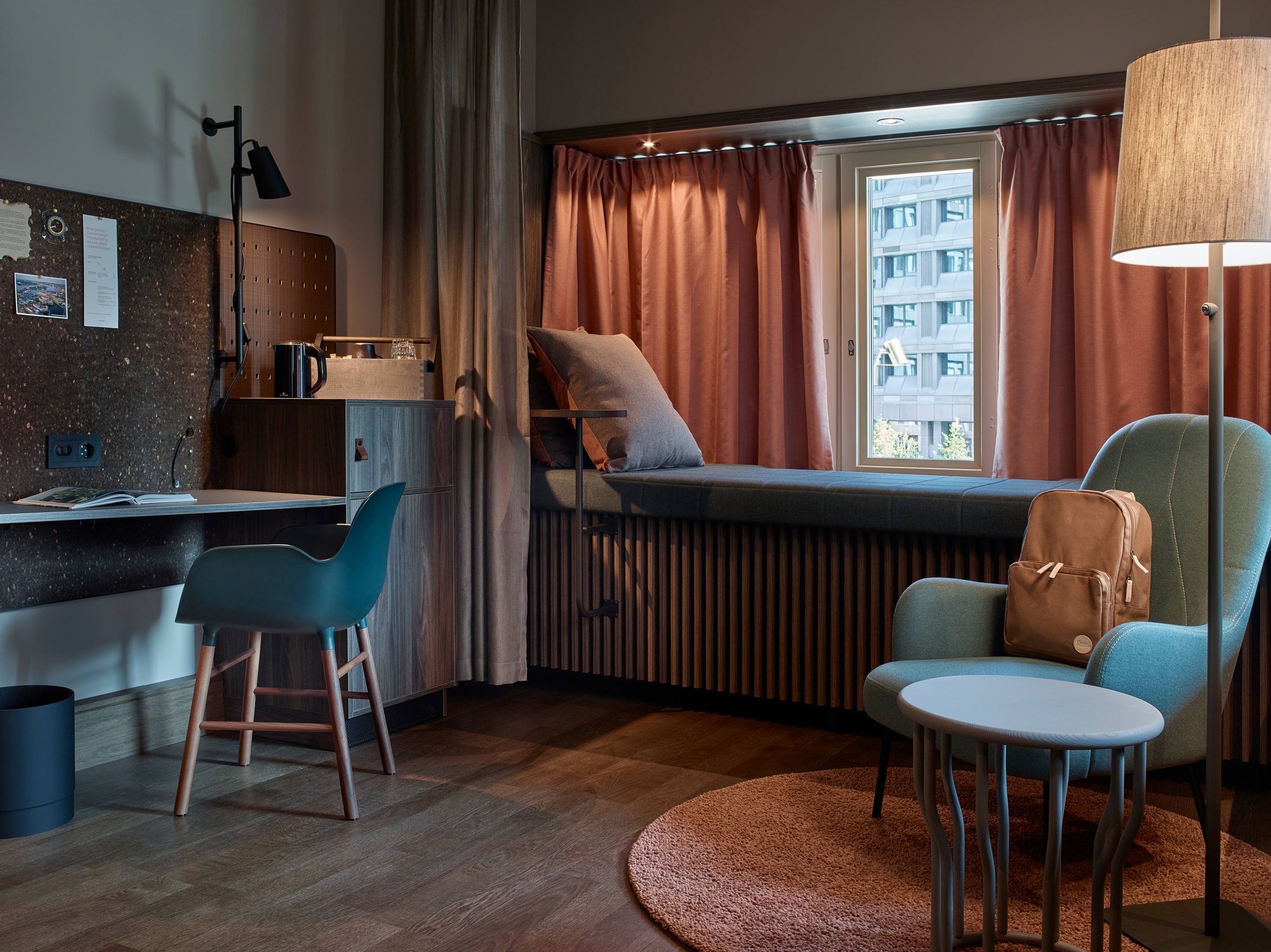 Skrivbord med stol samt fötölj och sittplats vid fönstret på Downtown Camper i Stockholm.