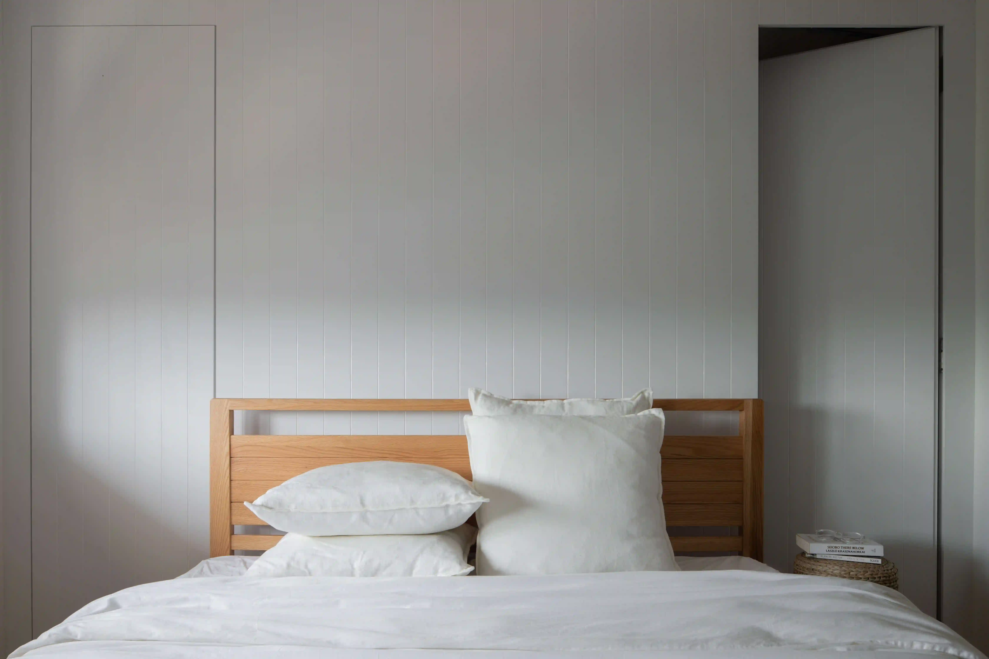 Scandinavian bedroom with white linens, oak headboard and hidden smart locks
