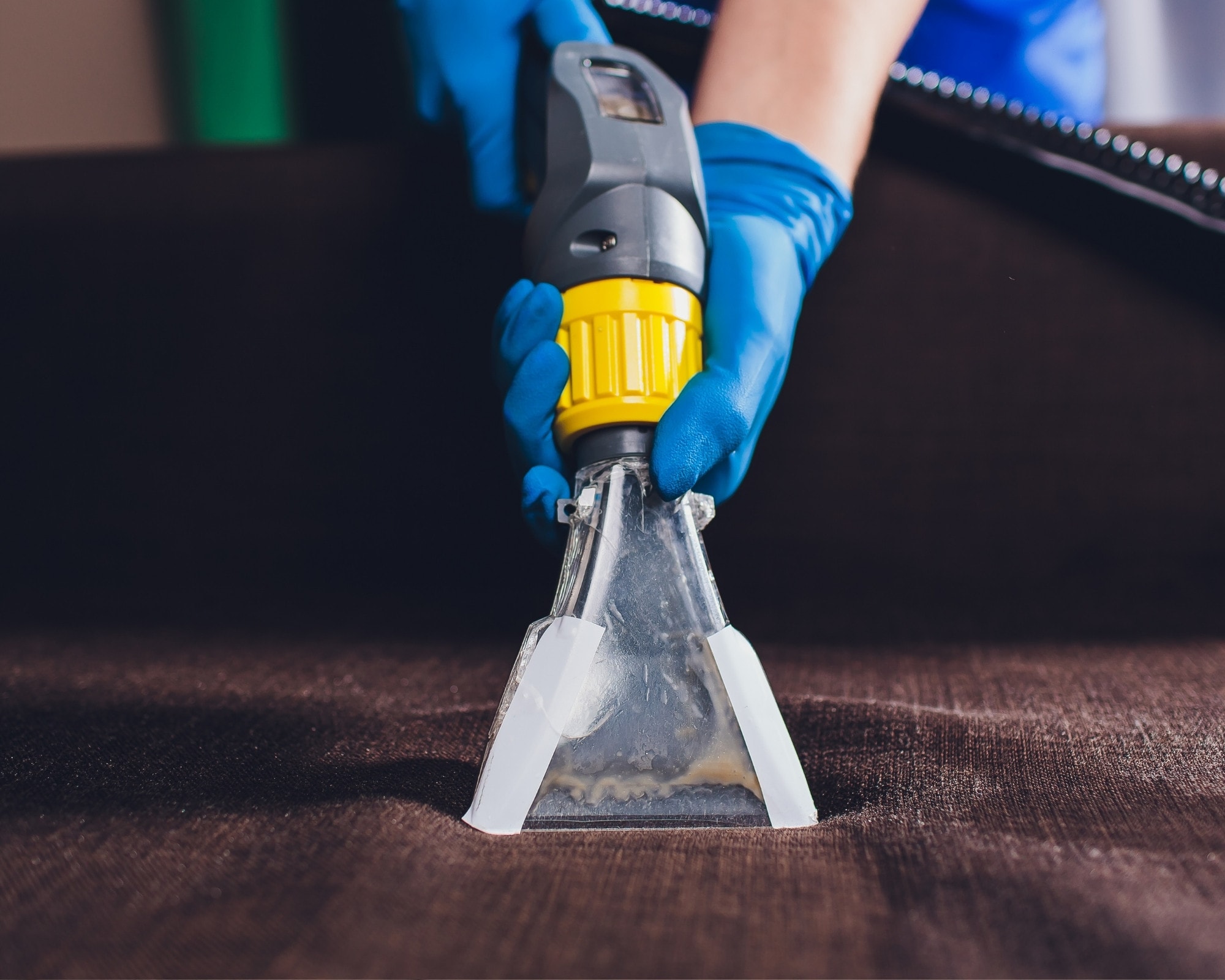 Professional sofa cleaning in progress on a dark fabric couch using an upholstery cleaner, demonstrating effective deep cleaning methods to refresh and sanitize sofas.