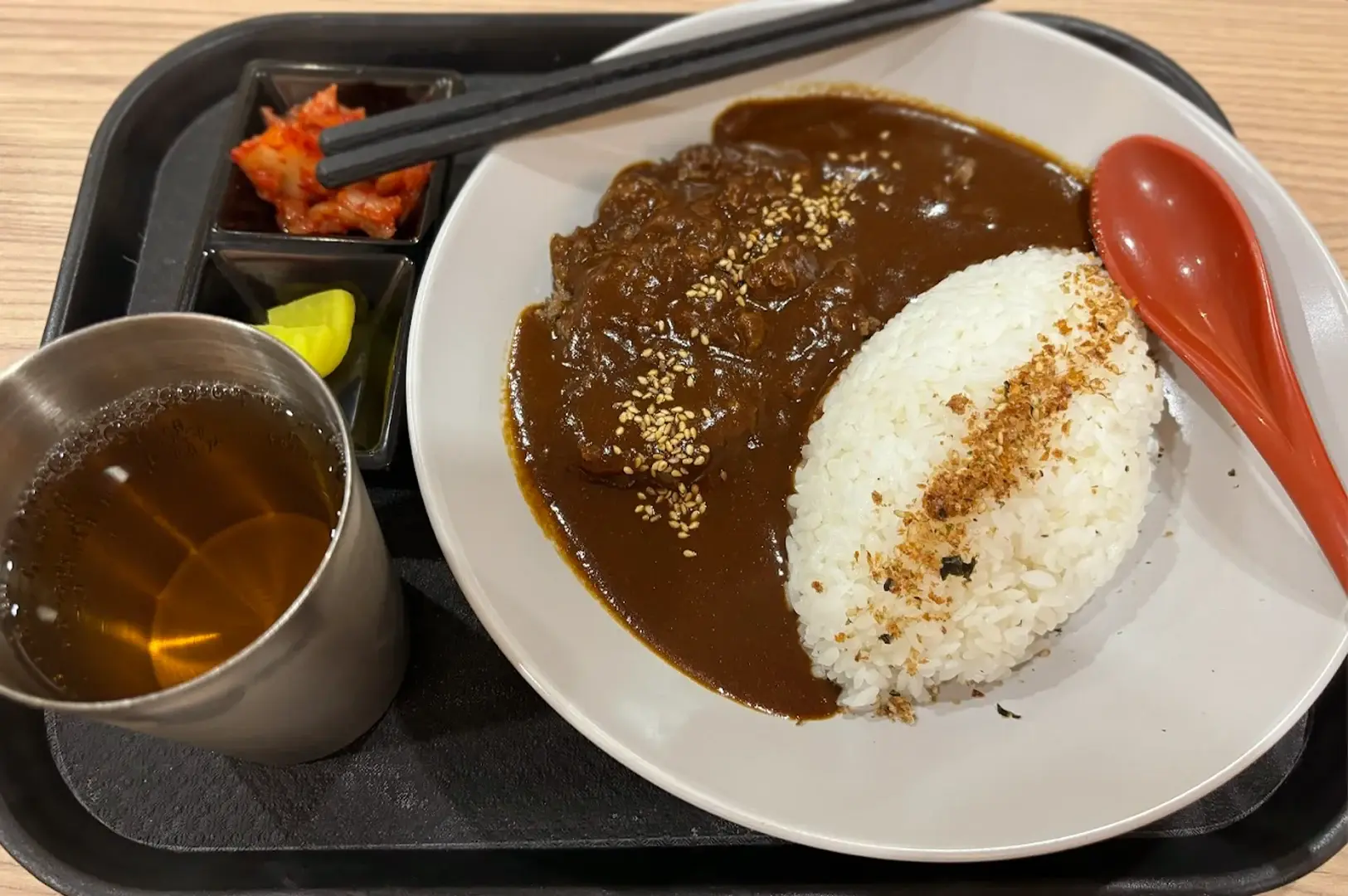 A hearty Japanese curry set from Kuro Kare in Singapore, featuring tender meat in a thick, dark curry sauce served with white rice and side dishes.