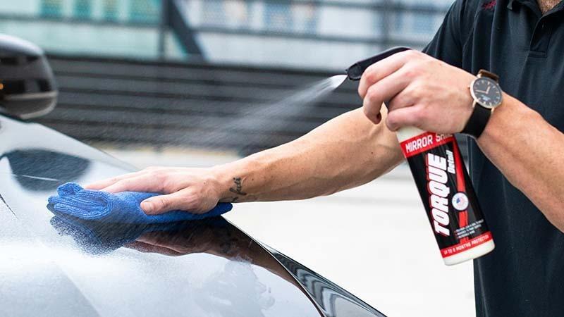 A man polishing his car with a microfiber towel