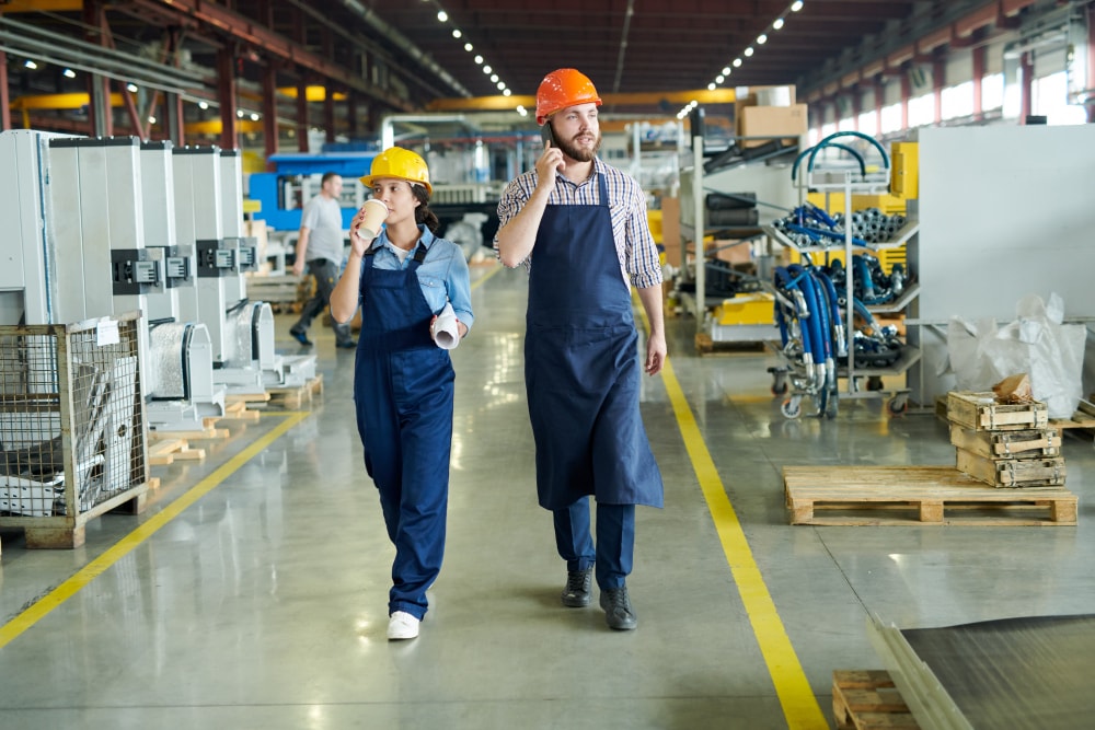 Factory workers crossing hall on a mobile phone thats connected to the business phone system.