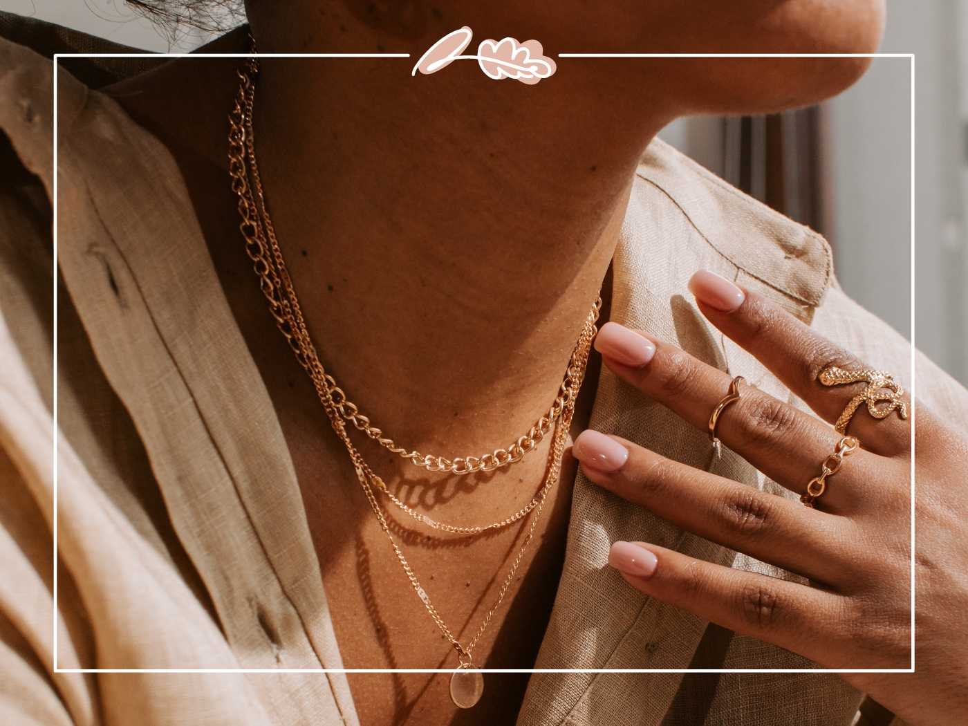 A woman's hand adorned with elegant gold jewelry, highlighting the intricate design of the necklaces and rings - Fabulous Flowers and Gifts.