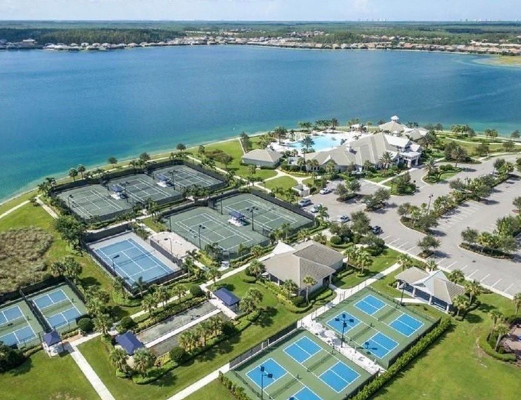 An aerial view of the Corkscrew Shores community in Estero, Florida, showcases a large central lake surrounded by beautifully designed single-family homes and lush nature preserves, highlighting the community's appeal as a master-planned, gated community. Residents enjoy access to various amenities, including a resort-style swimming pool, fitness center, and walking trails, all contributing to the luxurious lifestyle offered in this prime location.