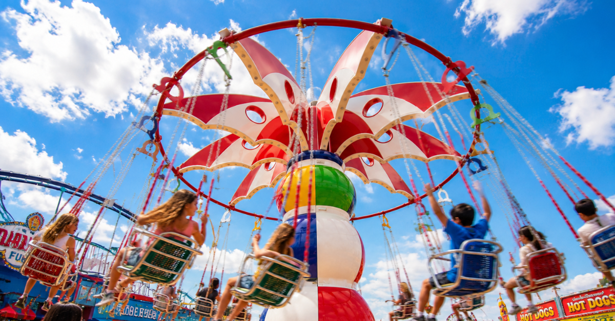 The image shows a vibrant amusement park scene at Fantasy Island in Beach Haven, featuring colorful rides and attractions under a bright blue sky, capturing the fun and lively atmosphere perfect for family entertainment on Long Beach Island.