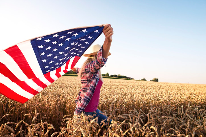 Woman waving an American flag in a cornfield. 