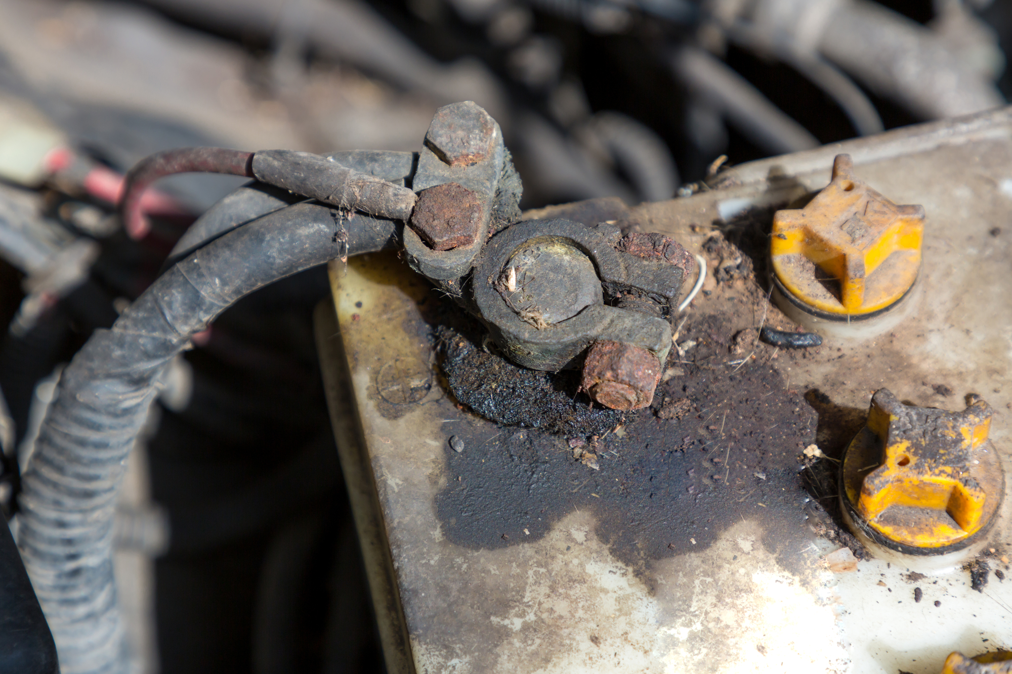 Corrosion and dirt on vehicle's battery positive terminal.