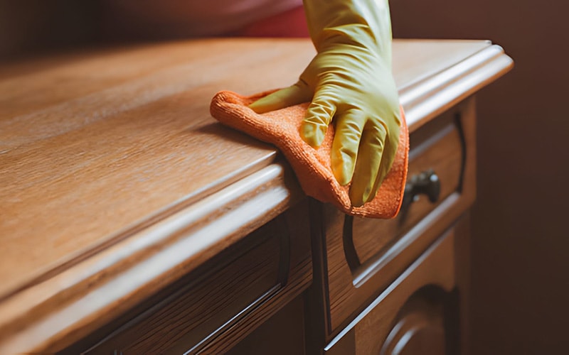 Wiping an old wooden desk with a microfiber cloth