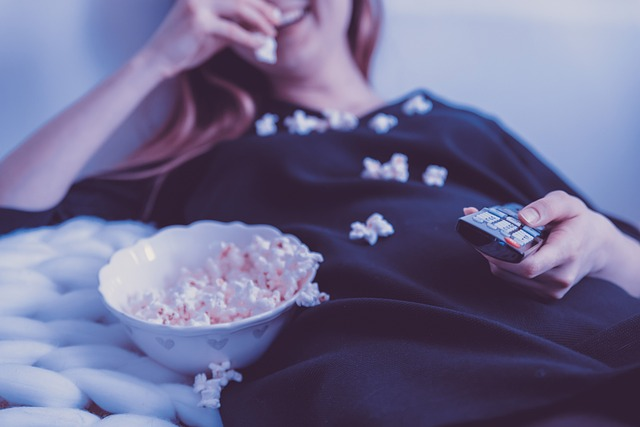 woman watching TV eating popcorn