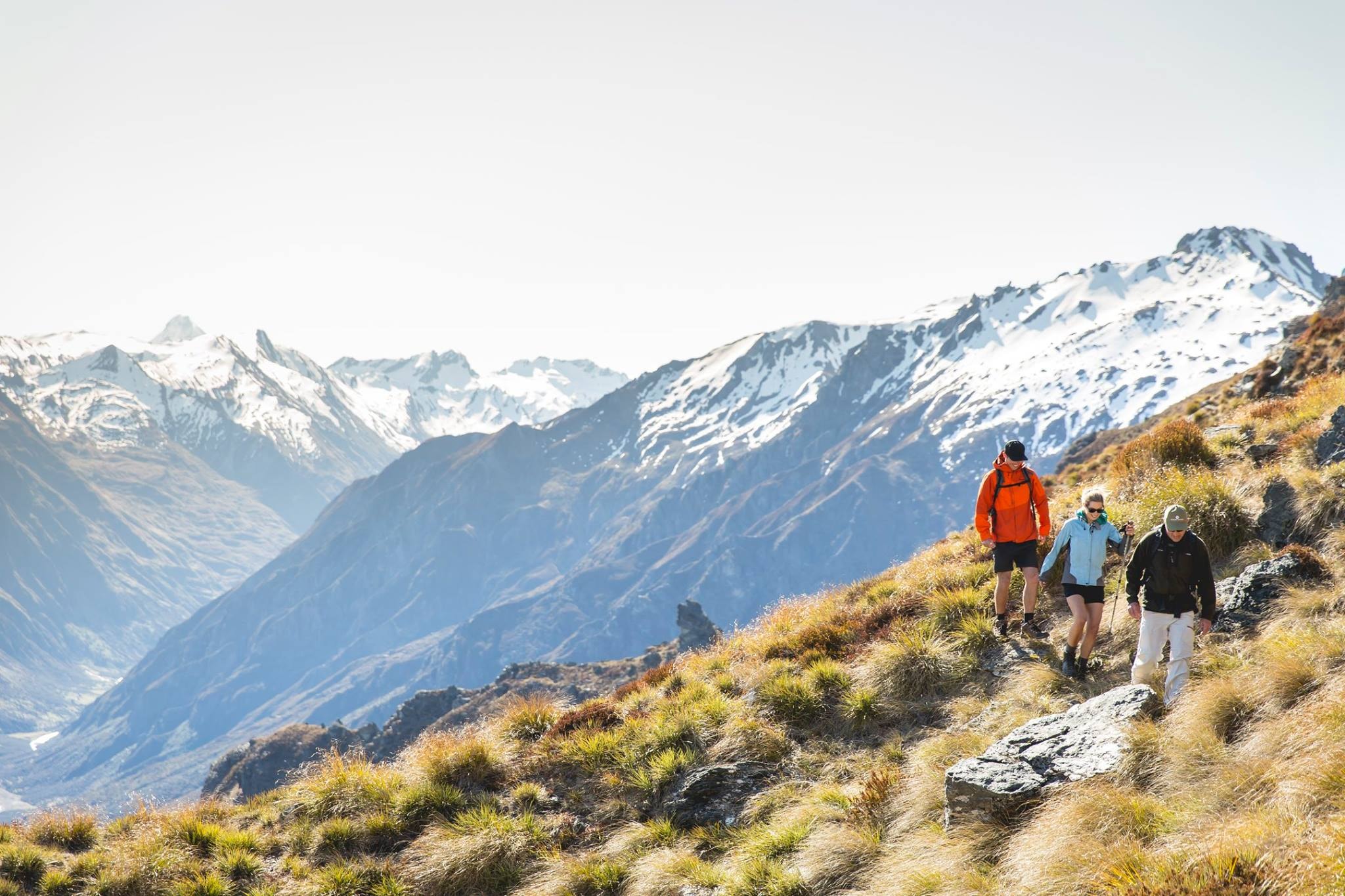 Couple hiking with guide through scenic alpine trails in New Zealand's Southern Alps during family adventure.
