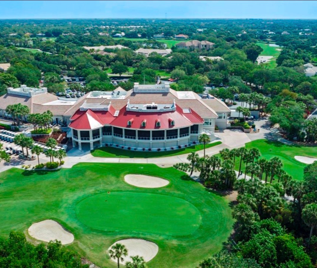An aerial view of Pelican Landing showcases its prestigious golf courses, beautifully designed residential areas, and preserved natural landscapes, highlighting the community's blend of luxury living and natural beauty in Bonita Springs, Florida. The image captures the amenity-rich environment, including the community pool, fitness center, and scenic boardwalks surrounded by tropical landscapes.