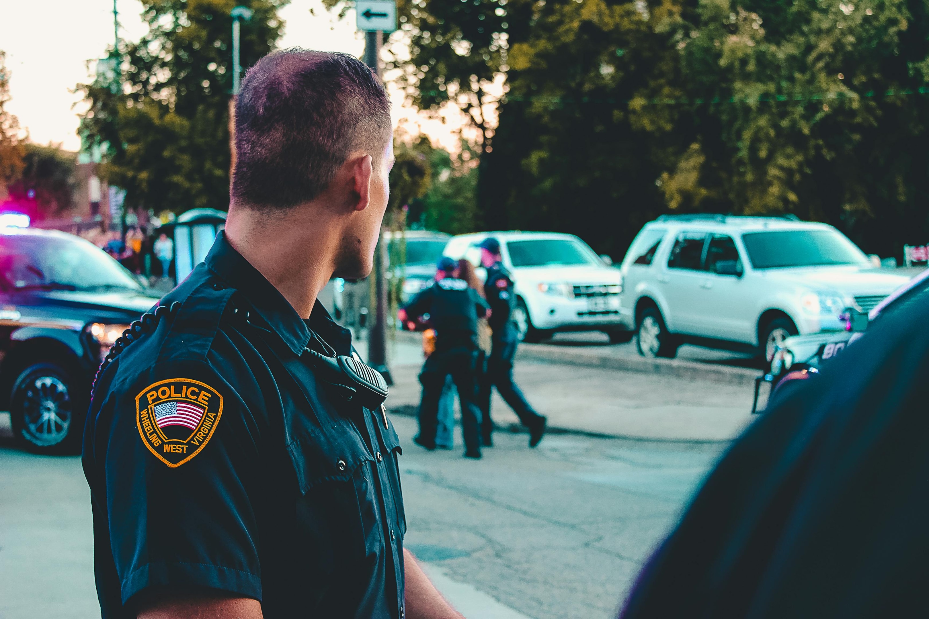 police officer looking on while 2 of his peers helps a woman to safety