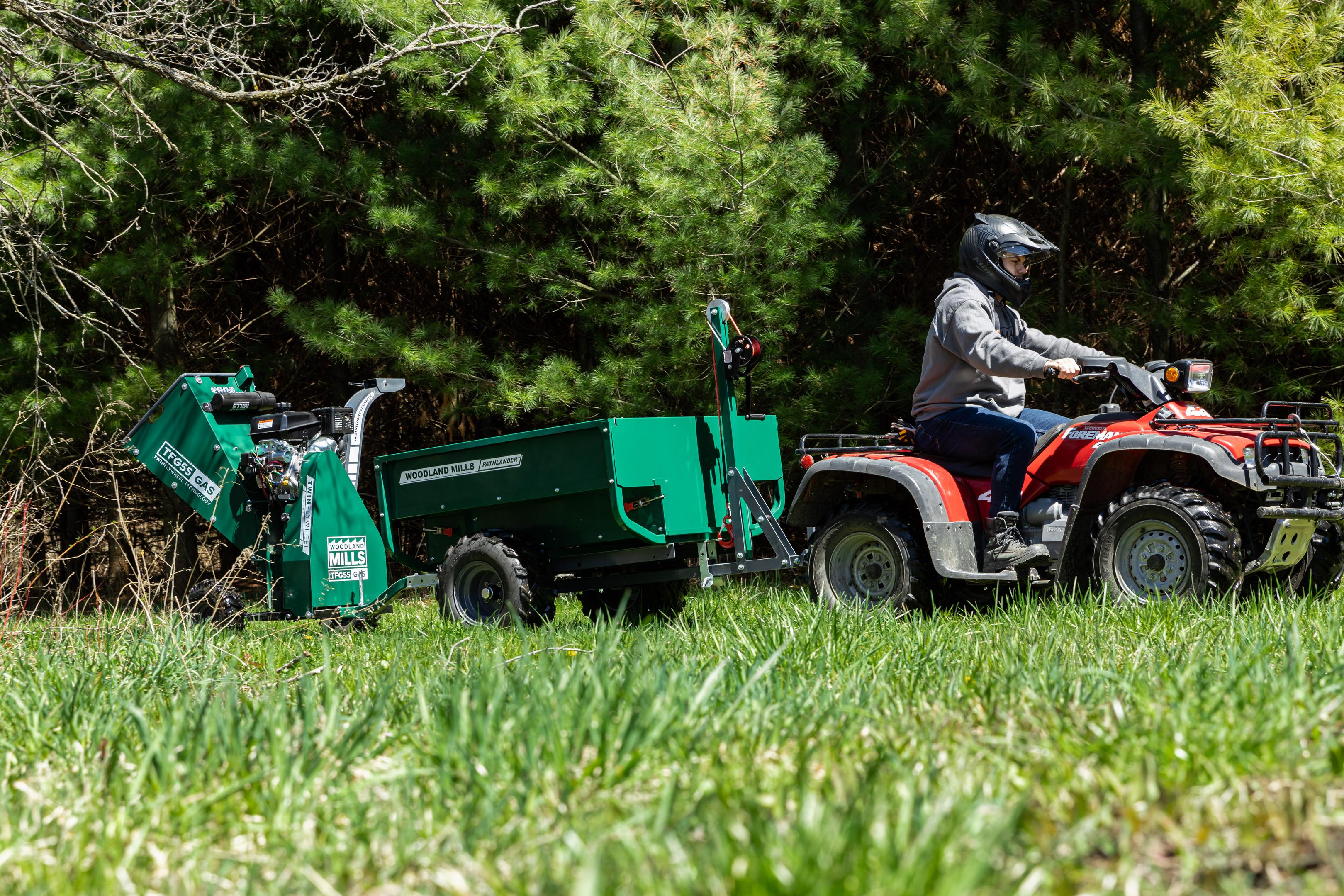A Woodland Mills wood chipper attached to a trailer attached to an ATV.
