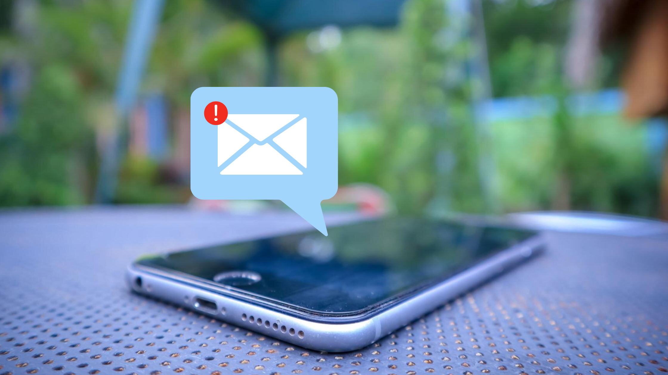 Smartphone on a table with an email alert graphic above it, symbolizing voicemail-to-email features in a cloud PBX.