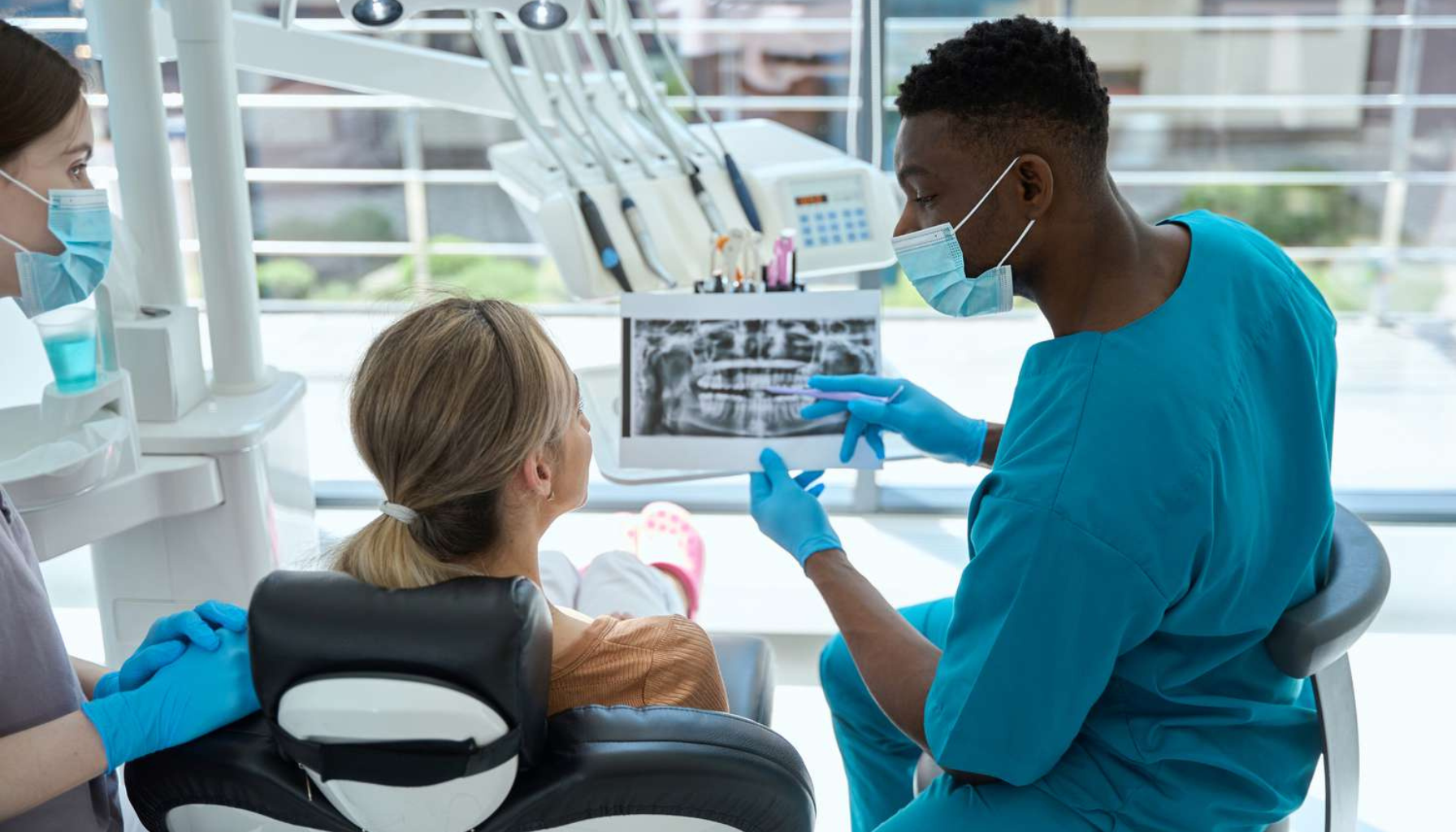 Pasient får forklart røntgenbilder av tannlege under konsultasjon.