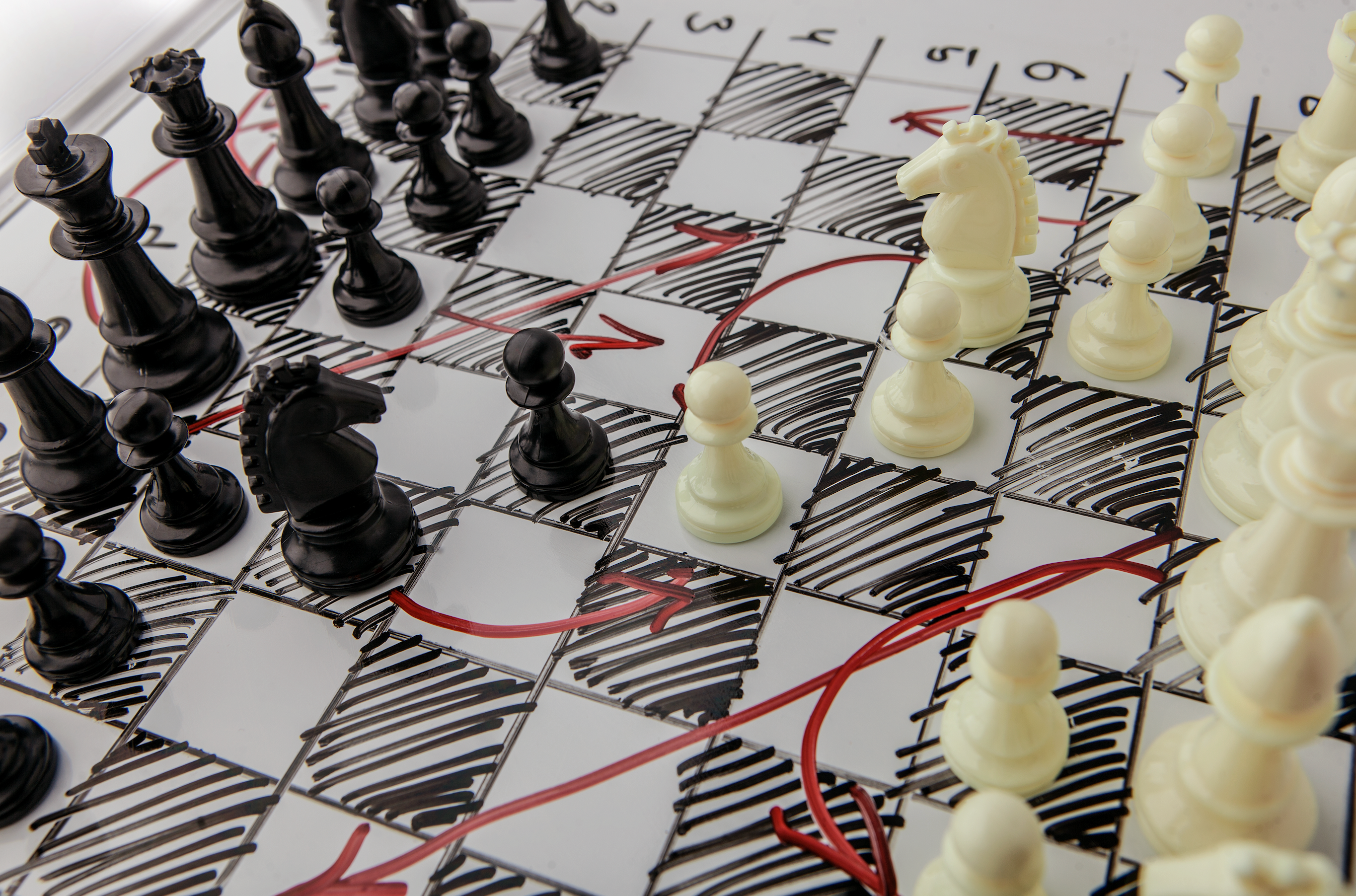 chess pieces sit on top of a drawn chessboard with red arrows pointing to the next move