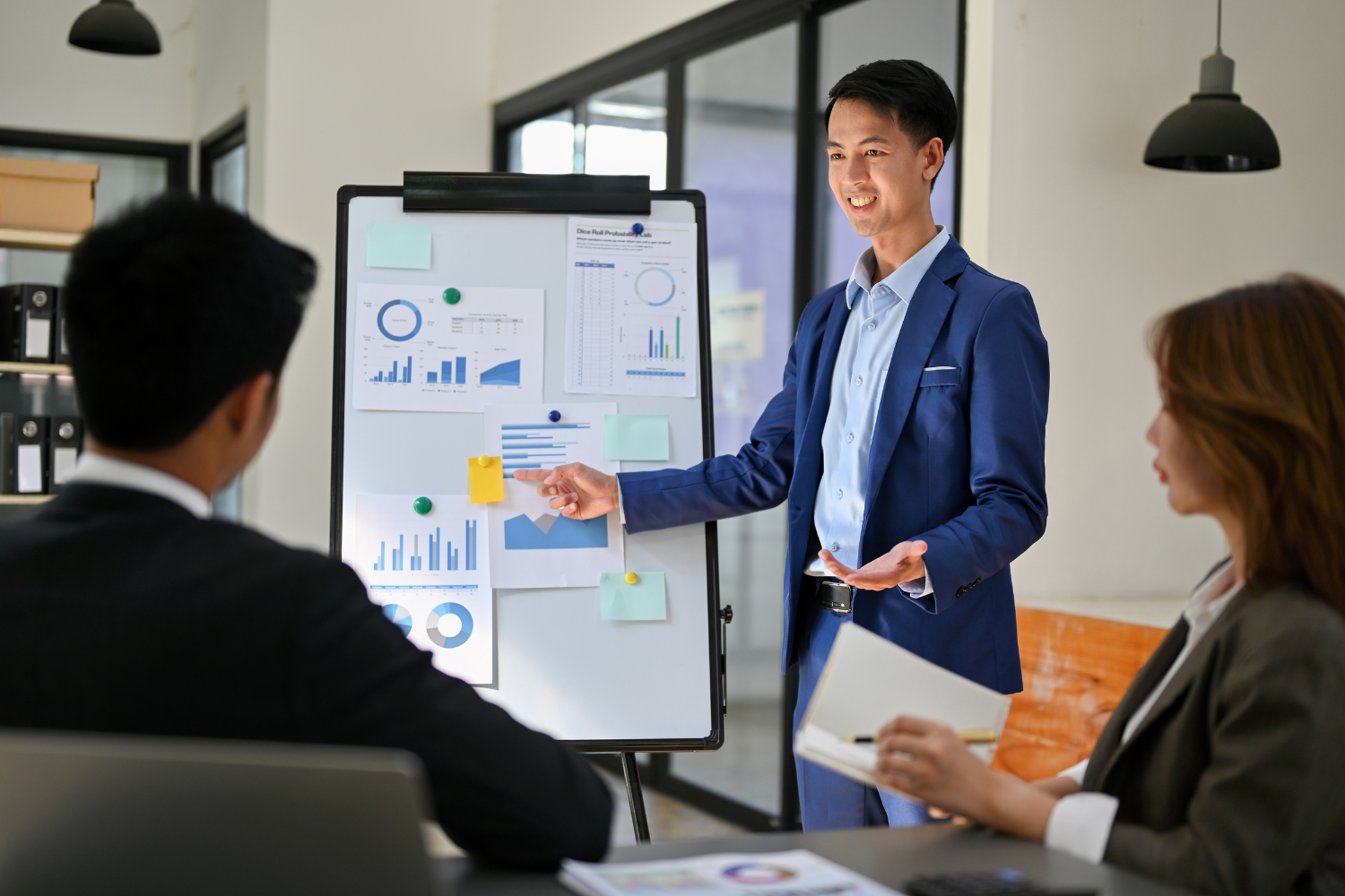 A Filipino junior employee leading a small team discussion.