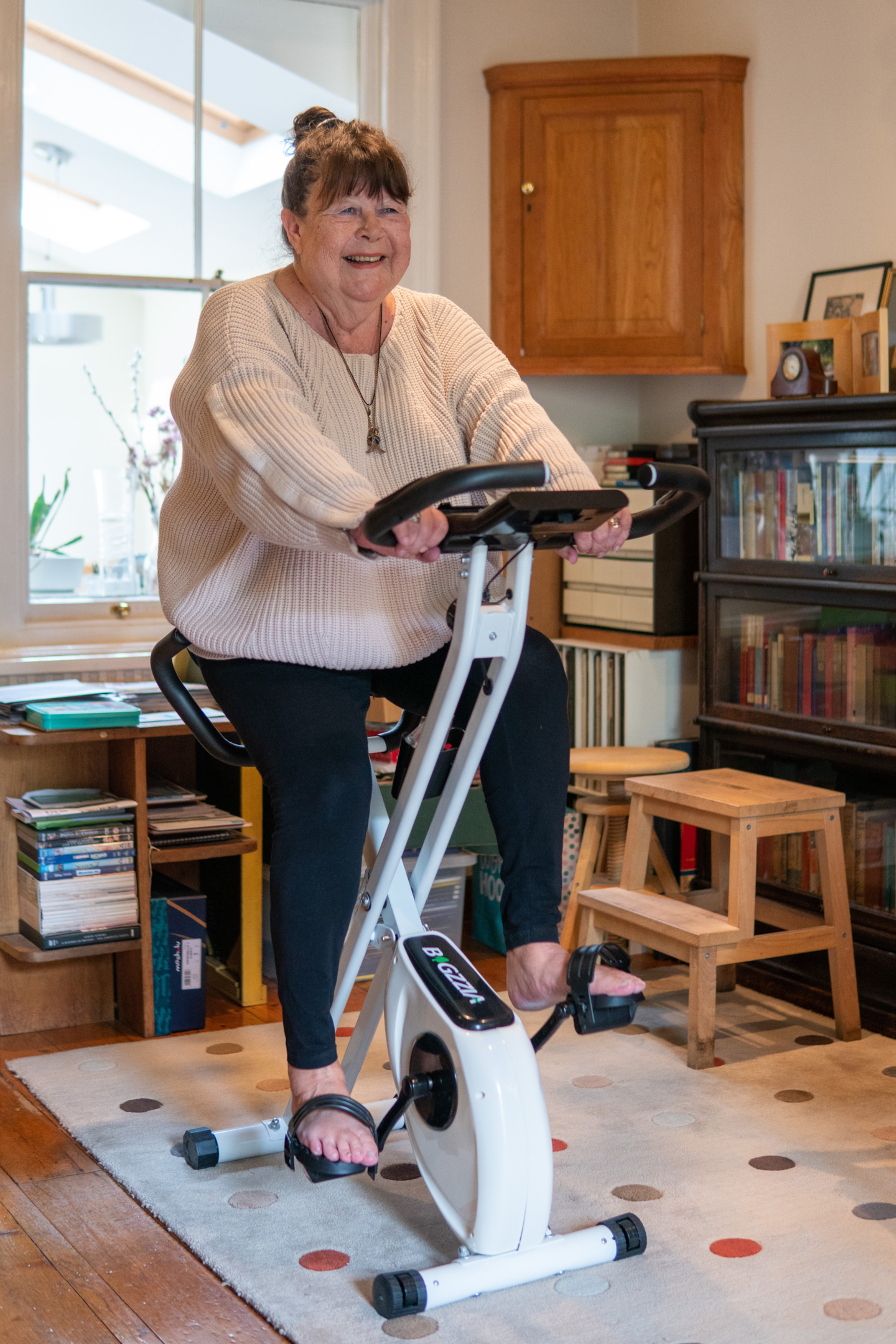 Idosa pedalando em bicicleta ergométrica. Foto de Centre for Ageing Better, Unsplash.