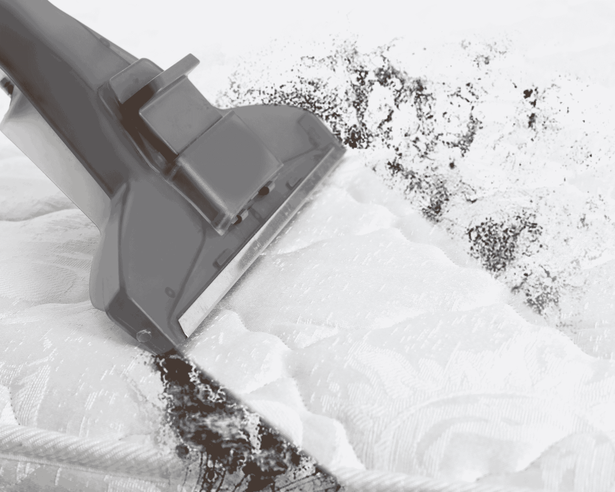 Close-up of a vacuum cleaner nozzle extracting dark dirt and debris from a stained white mattress. The contrast clearly shows the cleaned versus uncleaned areas, emphasizing the effectiveness of the cleaning process