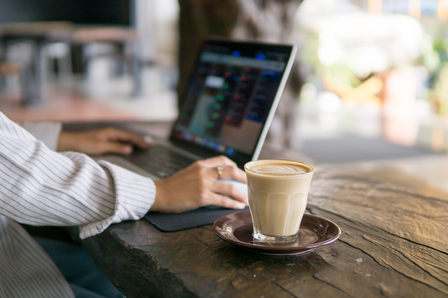 A remote worker working in a cozy café with a laptop.