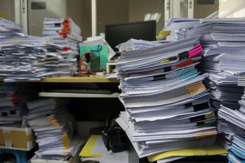 A cluttered desk with piles of paperwork representing the disorganized process of selling a small business